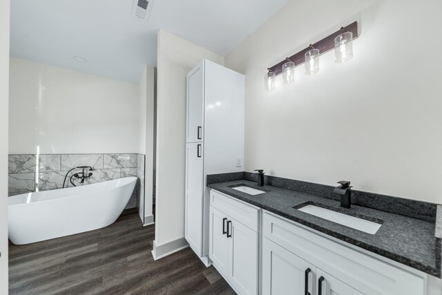 bathroom with hardwood / wood-style floors, a washtub, and vanity