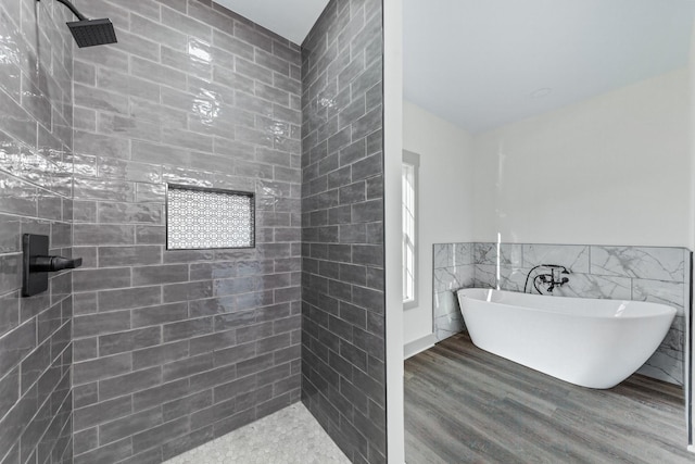 bathroom featuring wood-type flooring, a bathtub, and tile walls