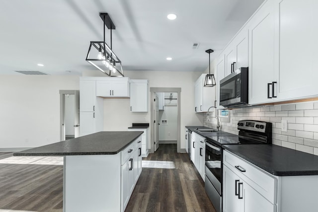 kitchen featuring hanging light fixtures, white cabinets, a center island, and stainless steel appliances