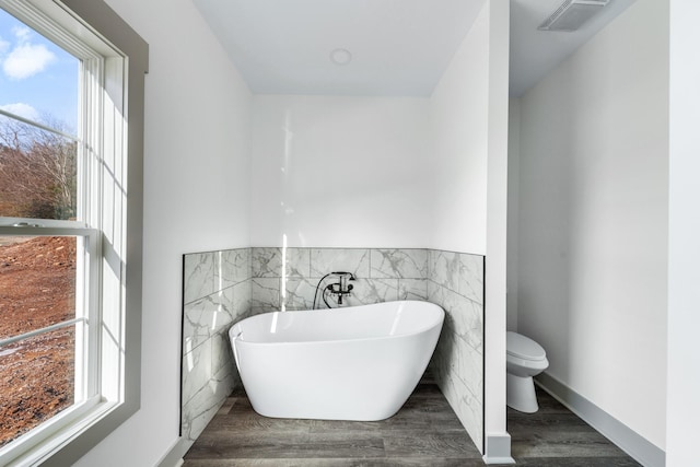 bathroom featuring toilet, wood-type flooring, and a washtub