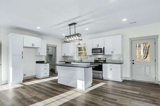 kitchen featuring pendant lighting, a center island, white cabinetry, dark wood-type flooring, and appliances with stainless steel finishes