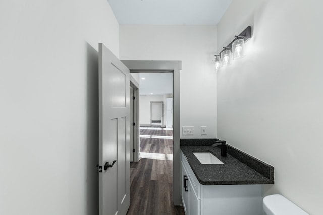 bathroom with toilet, vanity, and wood-type flooring