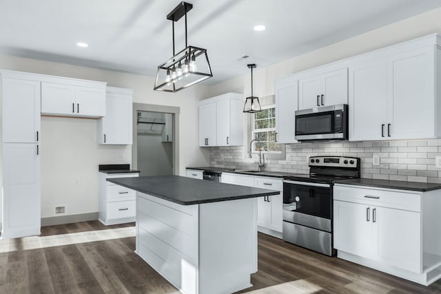 kitchen featuring white cabinets, appliances with stainless steel finishes, a kitchen island, decorative light fixtures, and sink