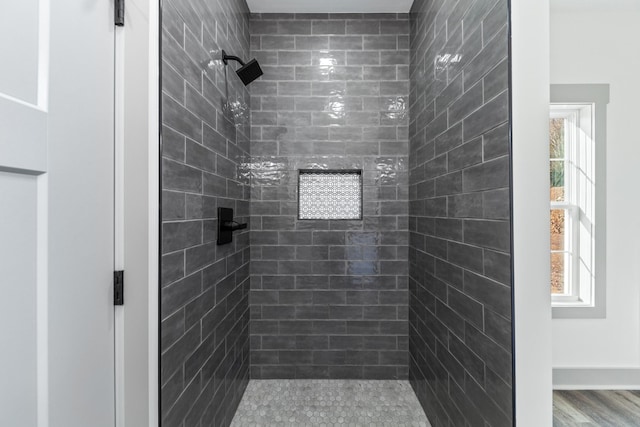 bathroom with hardwood / wood-style flooring and a tile shower