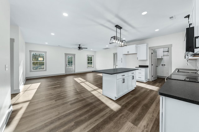 kitchen with ceiling fan, dark hardwood / wood-style flooring, hanging light fixtures, white cabinets, and a center island