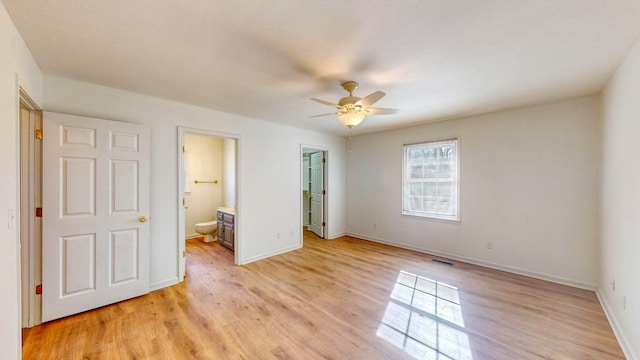 unfurnished bedroom featuring a spacious closet, ensuite bath, a closet, ceiling fan, and light hardwood / wood-style flooring