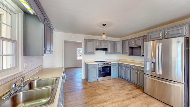 kitchen featuring pendant lighting, appliances with stainless steel finishes, sink, light wood-type flooring, and gray cabinetry