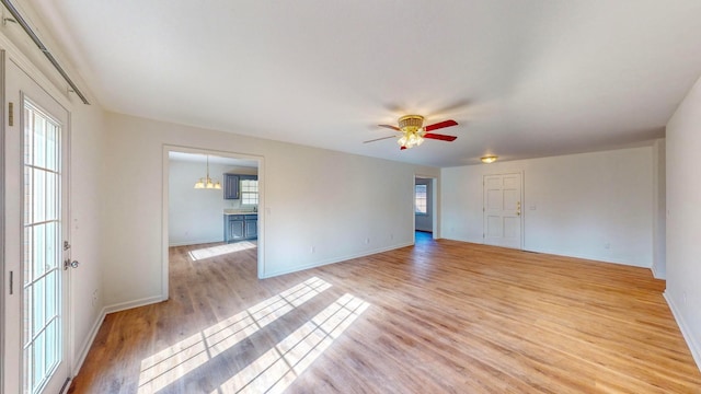 unfurnished living room featuring ceiling fan, light wood-type flooring, and plenty of natural light