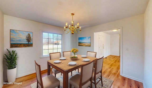 dining room with light wood-type flooring and a notable chandelier