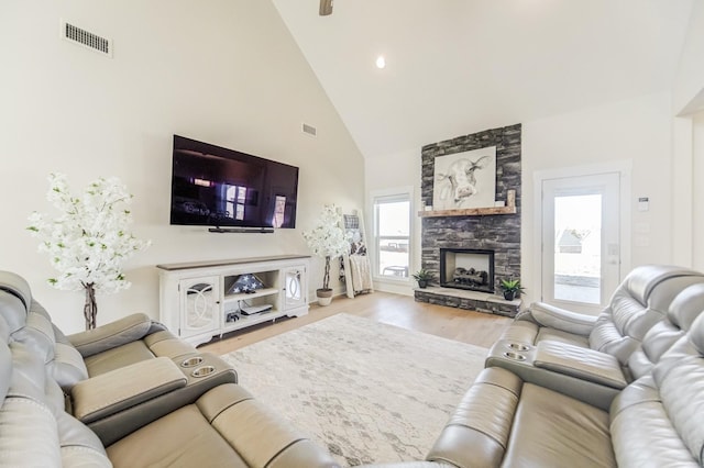 living room with high vaulted ceiling, light hardwood / wood-style flooring, plenty of natural light, and a fireplace