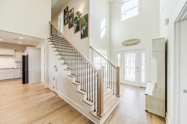 entryway featuring light hardwood / wood-style floors and a towering ceiling