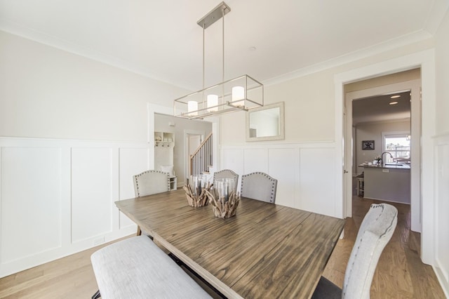 dining area featuring ornamental molding, a chandelier, and light wood-type flooring