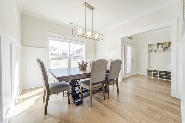 dining area with crown molding, light hardwood / wood-style floors, and a notable chandelier