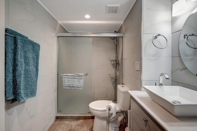 bathroom with a shower with shower door, tile walls, toilet, and vanity