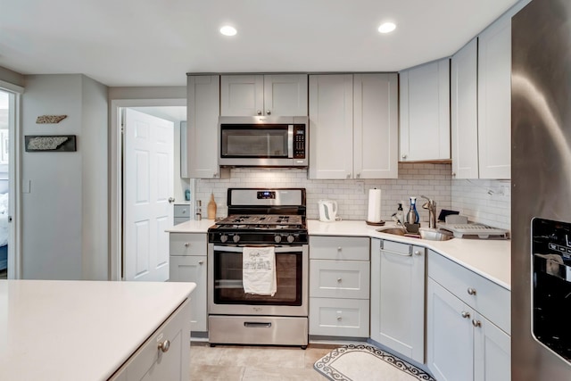 kitchen featuring tasteful backsplash, sink, gray cabinetry, stainless steel appliances, and light tile patterned floors