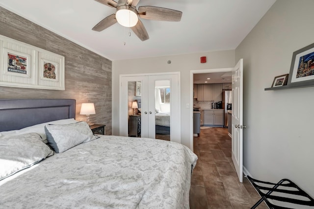 bedroom featuring ceiling fan, french doors, and wooden walls