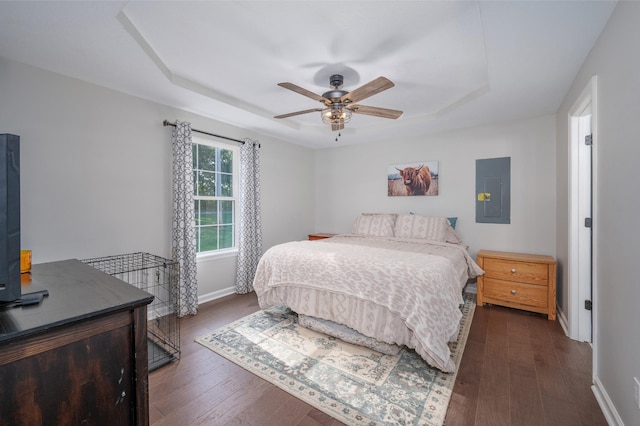 bedroom featuring ceiling fan, dark wood-type flooring, electric panel, and a raised ceiling