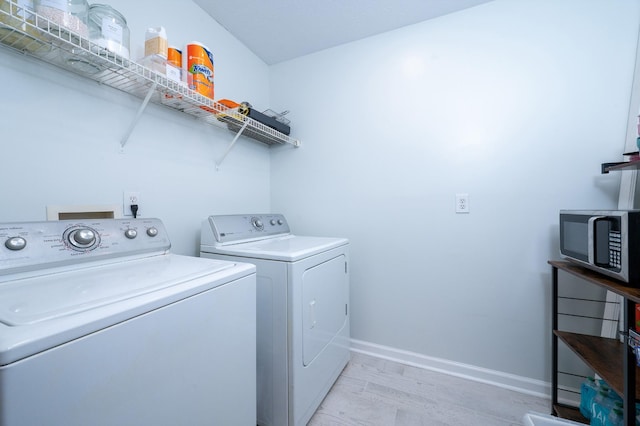 clothes washing area featuring light hardwood / wood-style floors and washer and clothes dryer