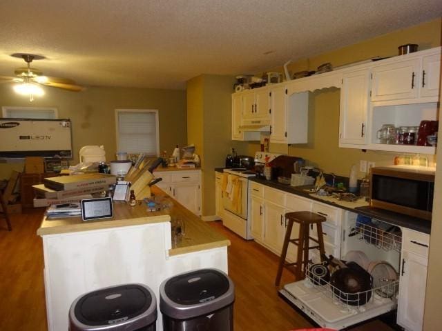 kitchen with white electric range, dark wood-type flooring, white cabinetry, and a center island