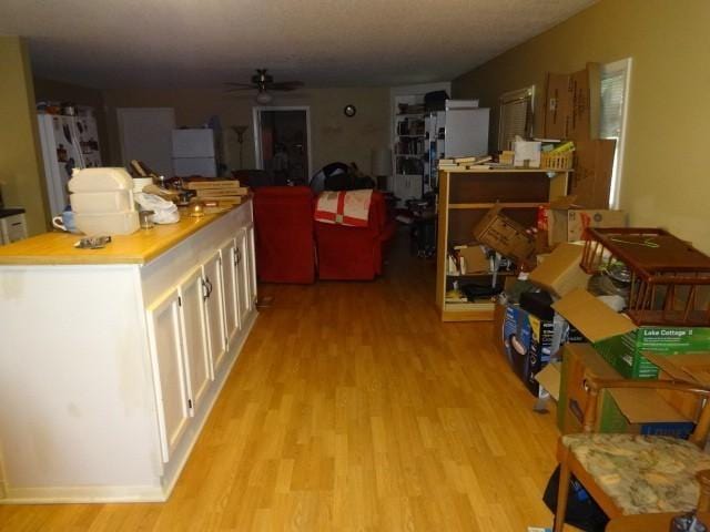 kitchen with ceiling fan, white cabinetry, and light hardwood / wood-style flooring