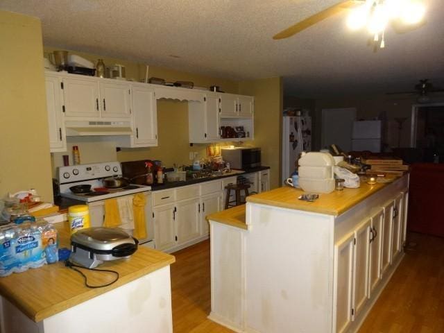 kitchen with a center island, white cabinets, and white appliances