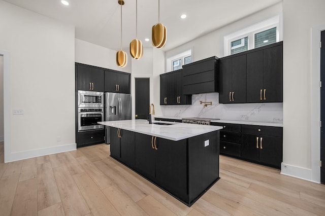 kitchen with sink, hanging light fixtures, an island with sink, a kitchen breakfast bar, and stainless steel appliances