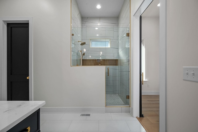 bathroom with a shower with door, vanity, and tile patterned flooring