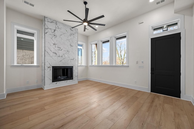 unfurnished living room with light hardwood / wood-style floors, ceiling fan, and a fireplace