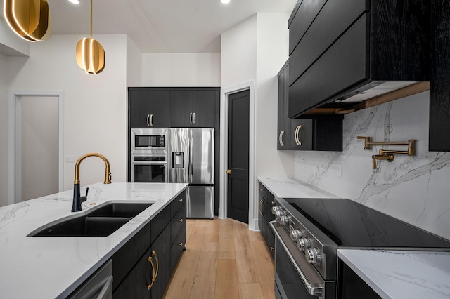 kitchen with decorative light fixtures, light stone countertops, sink, and stainless steel appliances