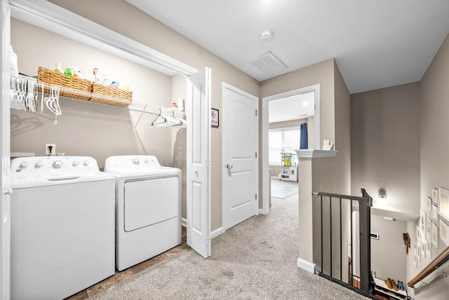 laundry area with washer and clothes dryer and light colored carpet