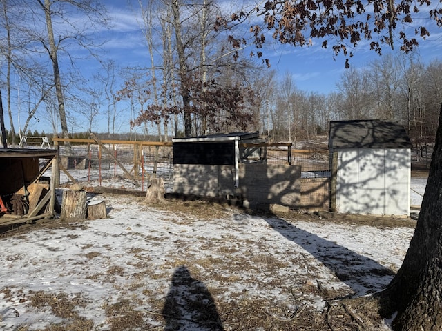 yard covered in snow featuring a storage shed