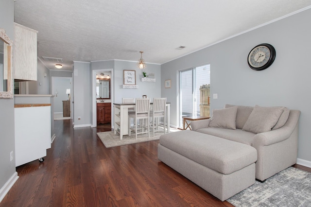 living room featuring dark wood-type flooring, a textured ceiling, and ornamental molding