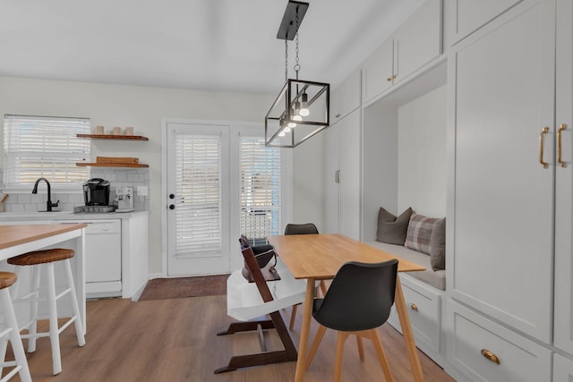 dining space with sink, light wood-type flooring, and a healthy amount of sunlight