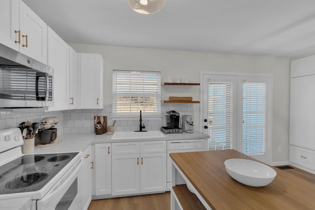 kitchen with decorative backsplash, sink, white cabinets, and white appliances