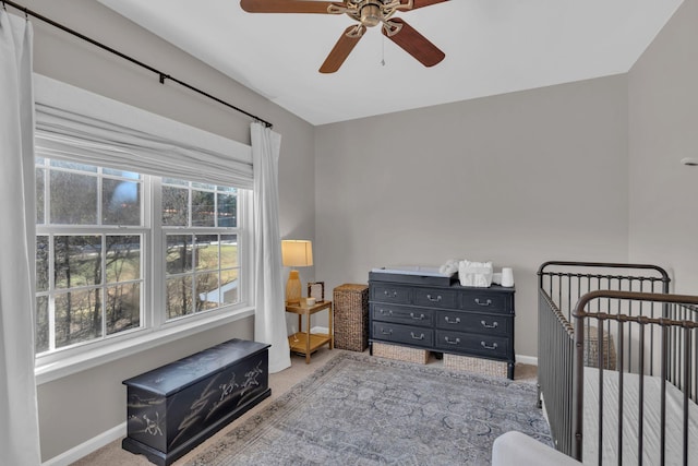 bedroom with ceiling fan, carpet flooring, and a crib