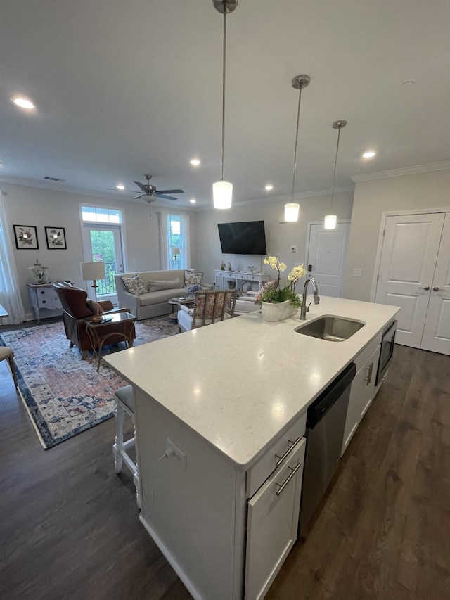 kitchen featuring a center island with sink, dark hardwood / wood-style floors, pendant lighting, stainless steel dishwasher, and sink