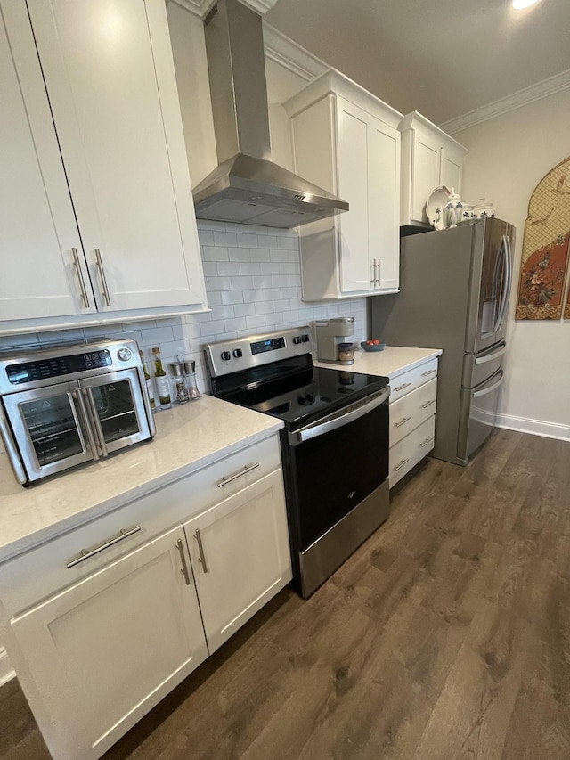 kitchen featuring tasteful backsplash, range hood, crown molding, white cabinetry, and appliances with stainless steel finishes