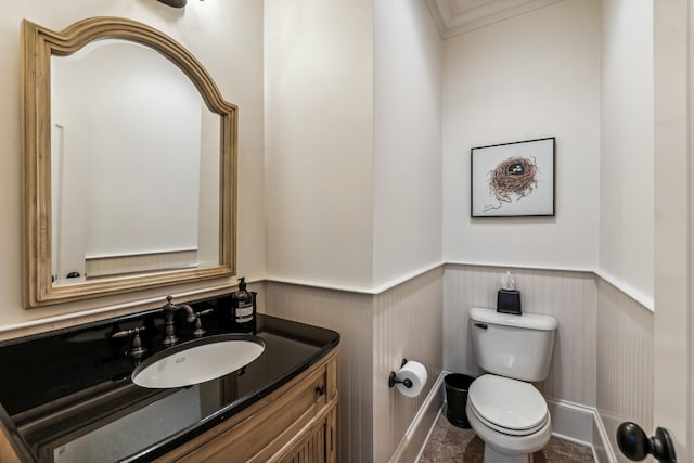 bathroom with toilet, vanity, and ornamental molding