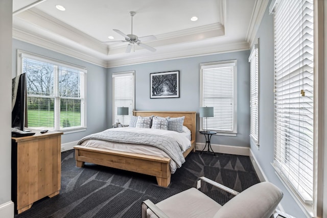 bedroom with a raised ceiling, ceiling fan, crown molding, and dark colored carpet