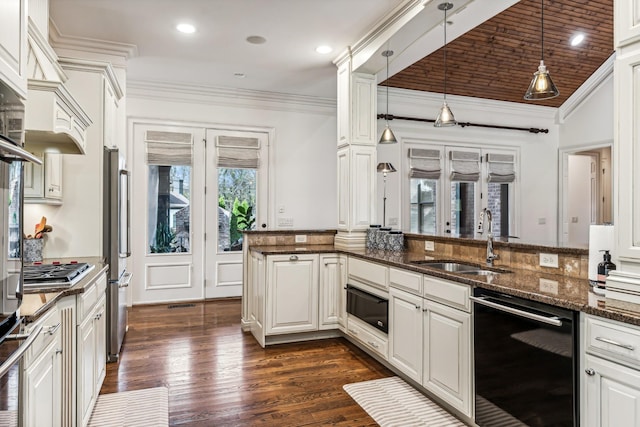 kitchen with decorative light fixtures, dark stone countertops, sink, stainless steel appliances, and white cabinets