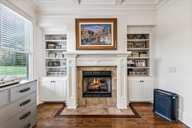 living room featuring built in shelves, dark wood-type flooring, a tile fireplace, and ornamental molding