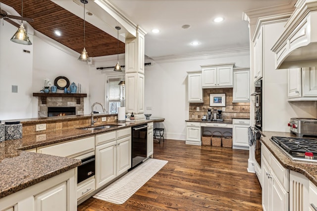 kitchen featuring premium range hood, pendant lighting, sink, white cabinetry, and dark stone counters