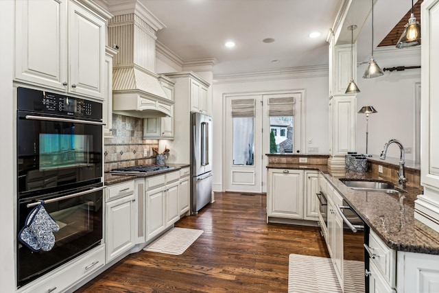 kitchen with appliances with stainless steel finishes, decorative light fixtures, dark stone counters, white cabinets, and sink