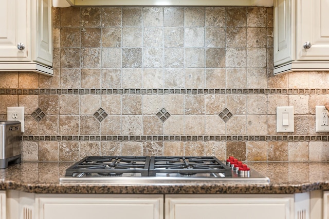 kitchen with stainless steel gas cooktop, white cabinets, and dark stone counters