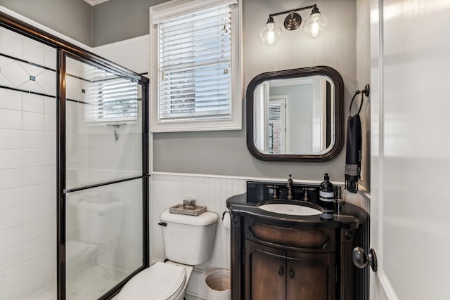 bathroom featuring toilet, vanity, and a shower with door