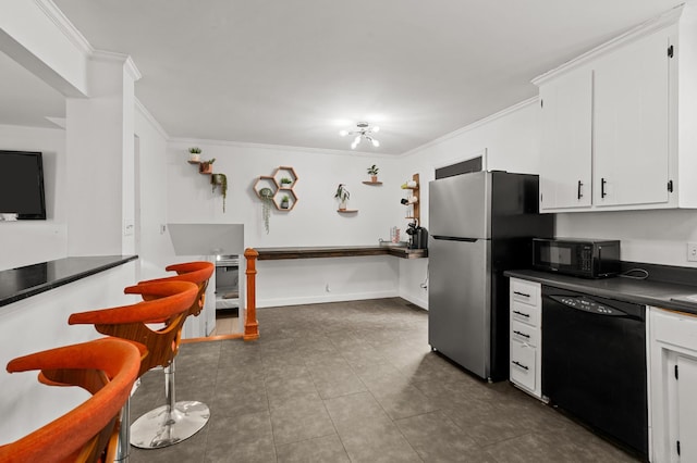 kitchen with crown molding, dark tile patterned flooring, white cabinets, and black appliances