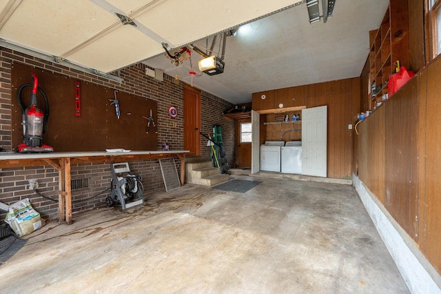 garage featuring a garage door opener, wooden walls, and washing machine and clothes dryer