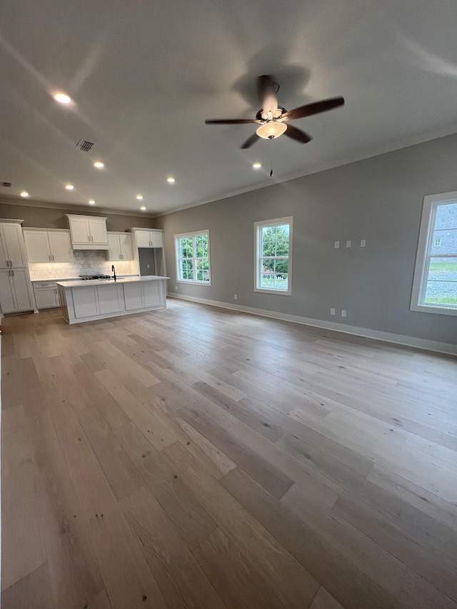 unfurnished living room with ceiling fan, crown molding, and light wood-type flooring