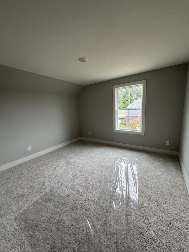 carpeted spare room featuring vaulted ceiling