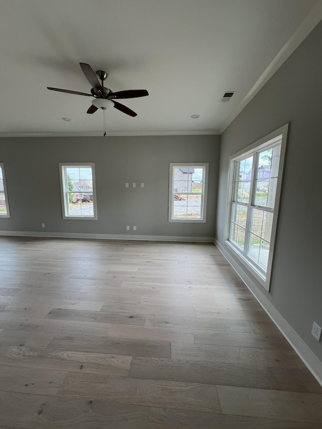 empty room with a healthy amount of sunlight, ornamental molding, and light hardwood / wood-style floors